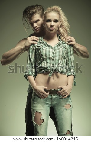 young fashion couple in casual clothes, man holding with hands on woman\'s shoulders