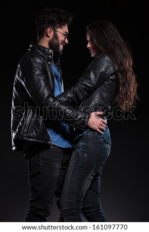 embraced smiling couple looking at each other on a dark background