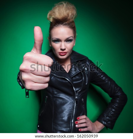 young positive fashion woman in leather jacket making the ok thumbs up sign