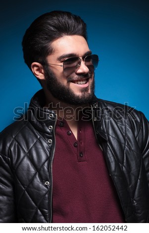 side portrait of a young man with nice hairstyle and beard smiling while looking away from the camera