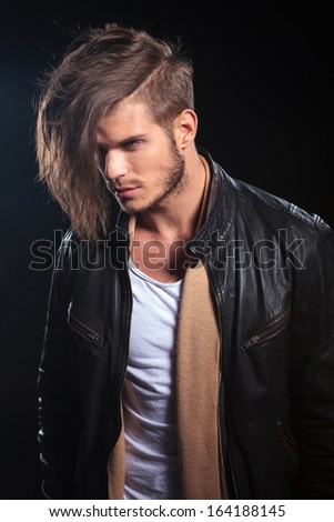 side view of a young fashion man in leather clothes looking away from the camera