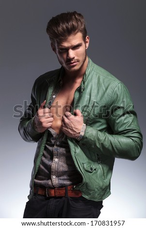 portrait of a fashion man pulling his shirt and jacket to reveal his muscular chest