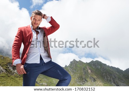 young man holding a trip bag walking in front of a mountain lake with cabin