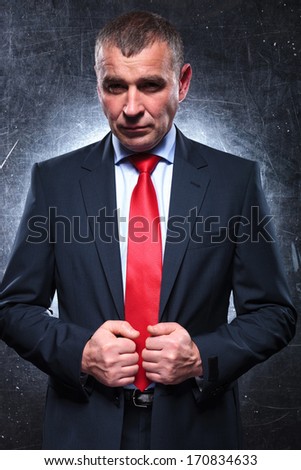 dramatic pose of a confident old business man pulling his suit and looking at the camera