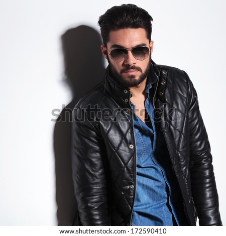 dramatic man in leather jacket and sunglasses posing for the camera in studio