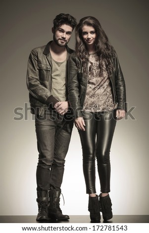 shy casual man standing next to a beautiful woman dressed in leather jacket and pants