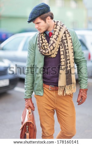 side view of an elegant young fashionable man posing for the camera outside