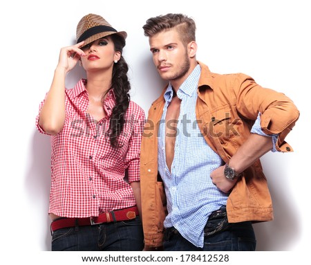 young casual fashion models posing in studio, woman looking at the camaera and man looking away to his side