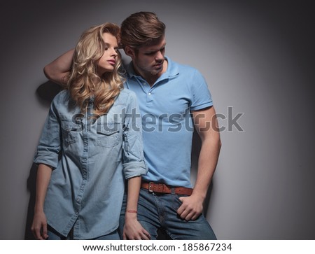 fashion couple in a sexy pose looking to their side against gray studio wall