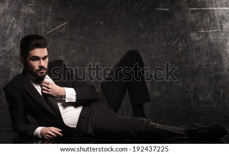 young elegant business man with beard fixing his tie on the floor of the studio