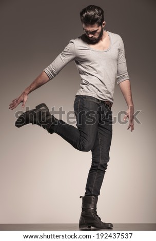 playful young fashion model in a dynamic pose on gray background
