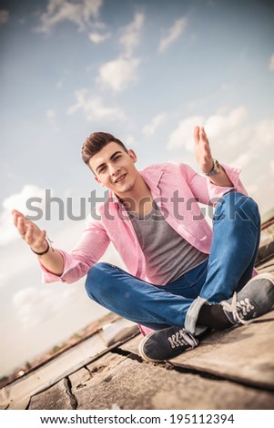 young casual man is welcoming you to sit with him on the roof top