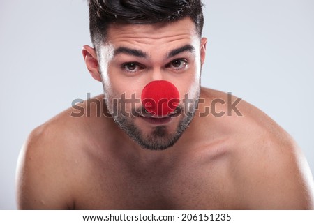 face of a naked man wearing a red nose like a clown studio picture