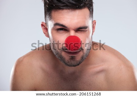 young naked man with red nose winking his eye and smiles