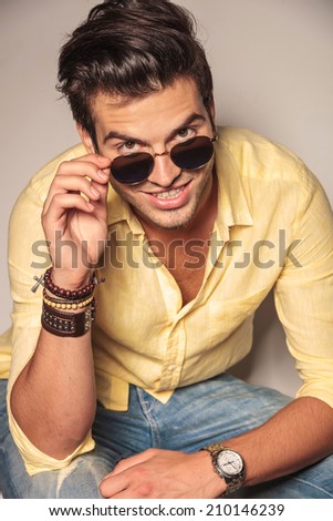 fashion man looks up and takes off his sunglasses, laughing to the camera