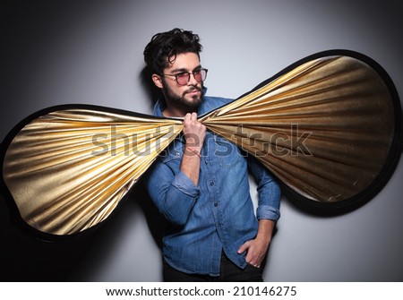 funny picture of young fashion man holding a big bow tie and looks to side