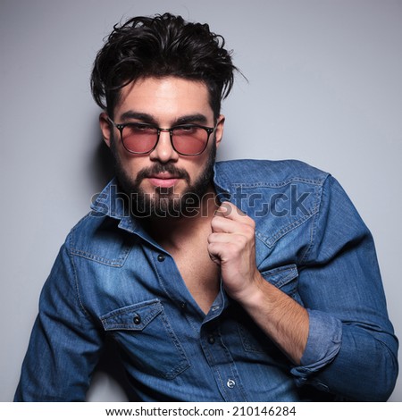 fashion man pulls his collar and looks to the camera in studio