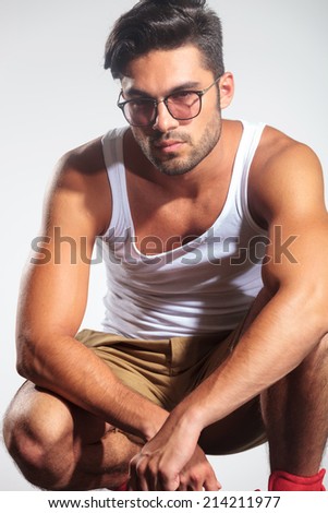 serious casual man in undershirt standing crouched in studio