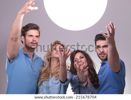 casual group of people reaching out for a big ball of light to tell them their future