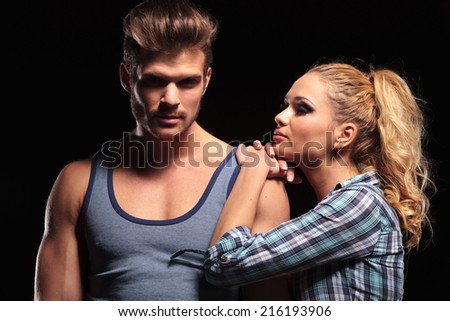 Blonde sexy woman resting her hands and chin on her boyfriend shoulder. The man is looking at the camera.