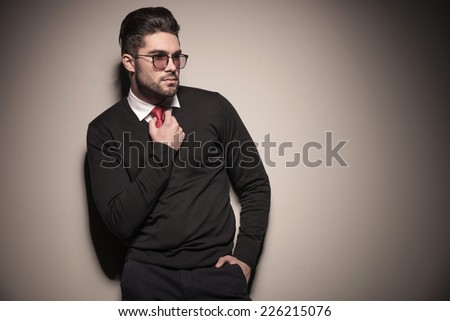Picture of a handsome business man looking away from the camera while fixing his tie.