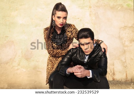 Beautiful fashion woman holding her hands on her lovers shoulders, bolt looking at the camera.