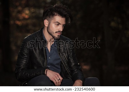 Side view of a casual fashion man relaxing in the park, looking away from the camera.