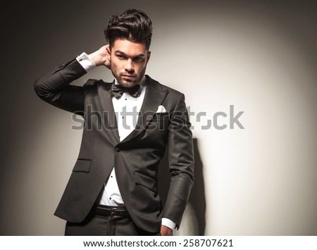 Handsome business man scratching his head while looking away from the camera, holding one hand in his pocket.