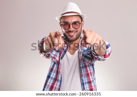 Portrait of a handsome young man smiling while pointing at you with both hands.