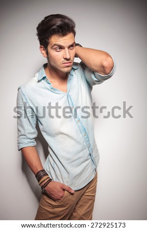 Smart casual man posing with his hand behind his neck while holding one hand in his pocket.