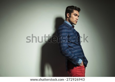 Side view picture of a handsome fashion man standing with his hand in pockets.