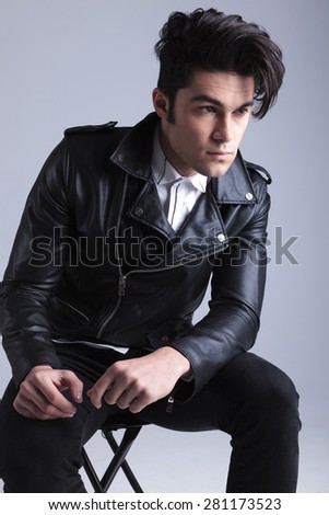 Handsome young casual man looking away from the camera while sitting on a chair.
