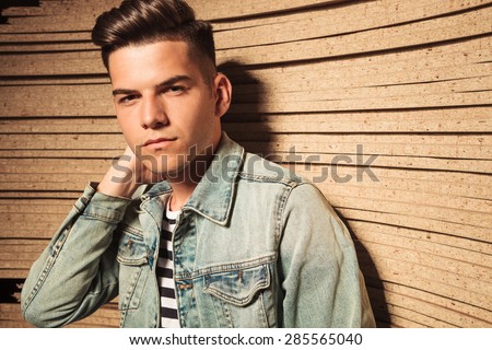 portrait of a cool casual young man with hand behind his neck looking at the camera