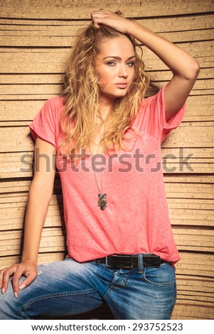 cool casual woman in jeans and shirt holding her hair up and looks at the camera