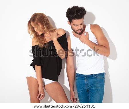 Fashion man and woman posing on white studio background while looking down.