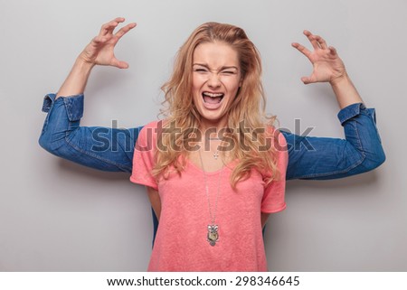 Casual young woman screaming while her boyfriend is holding his hands up behind her