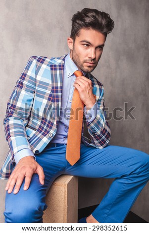 Business man fixing his tie while sitting on a wood box.