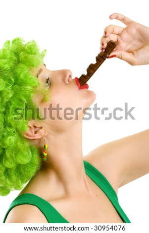 closeup of an attractive woman with green wig sucking on  a chocolate bar
