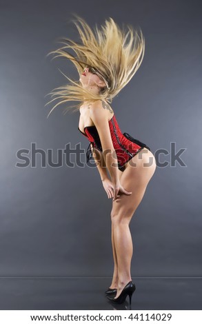 sexy blond woman in lingerie with fluttering hair over dark background