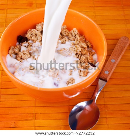 Cereals in bowl and milk pouring over it