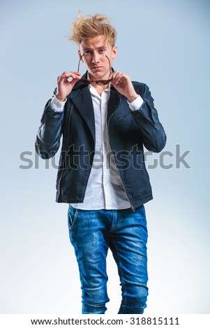 young man posing while taking sunglasses off and looking straight at the camera
