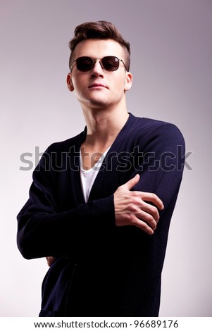 Studio shot of a handsome young male model wearing casual clothes and sunglasses on gray background