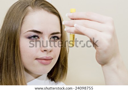Beautiful young female researcher holds analysis test tube in a hand
