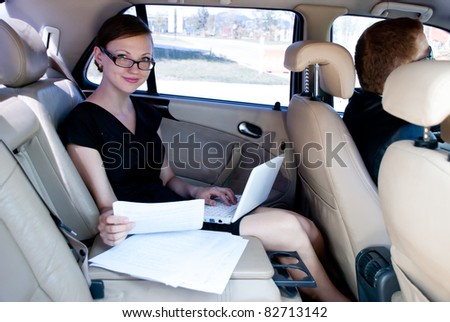 business travel: busy businesswoman with document and laptop in car