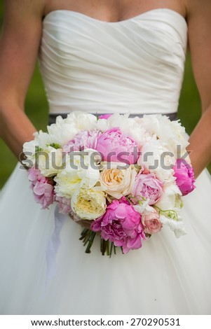 Bride holding wedding bouquet with Peonies, garden Roses, and Sweet pea flowers