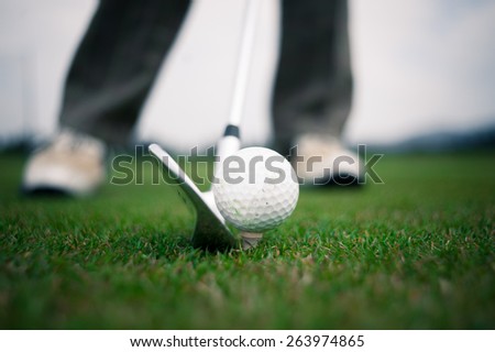 Playing golf, ball on tee and golf club about to shot