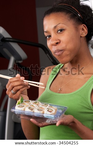 a woman eats sushi in a gym