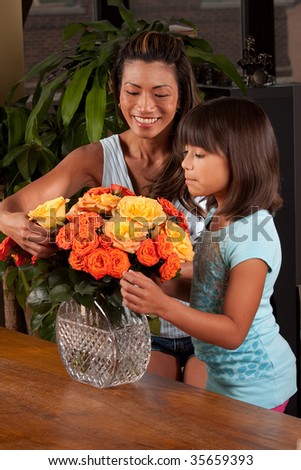a young girl helps her mom put together a flower arrangement, the camera is mostly focused on mom