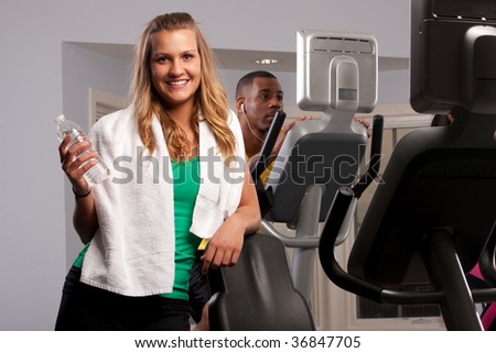 a couple of friends at the gym doing cardio with a girl in the front