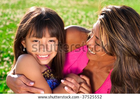 daughter looking into camera as her mom smiles at her